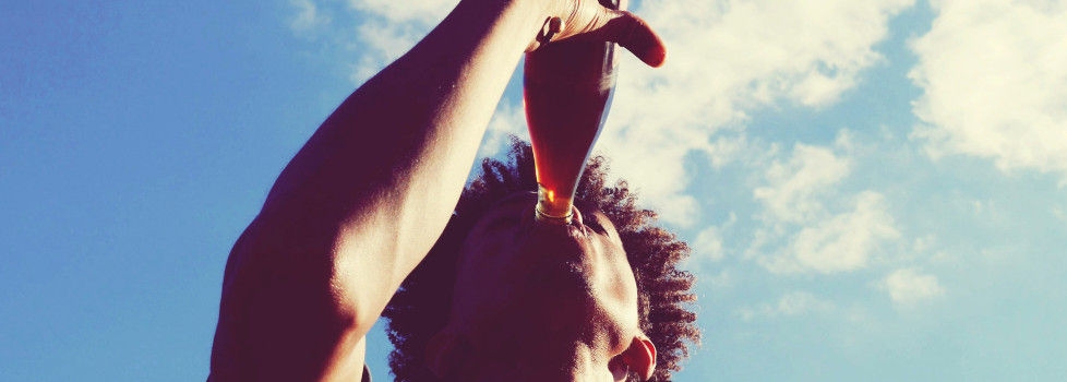 Low Angle View Of Man Drinking Cola Against Sky