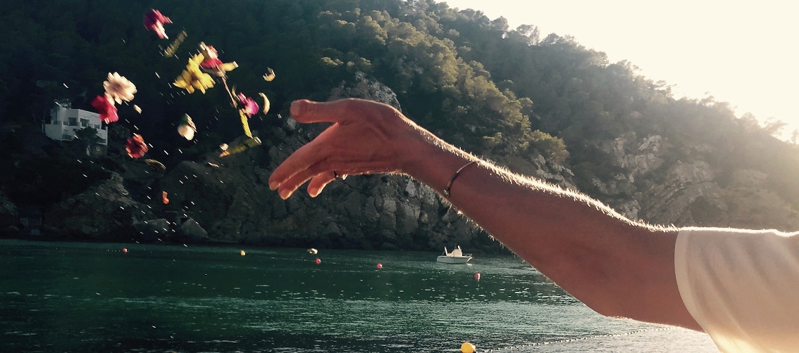 Person Throwing Flowers In Sea